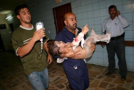 a wounded child in iraqi being carried by a member of hospital staff